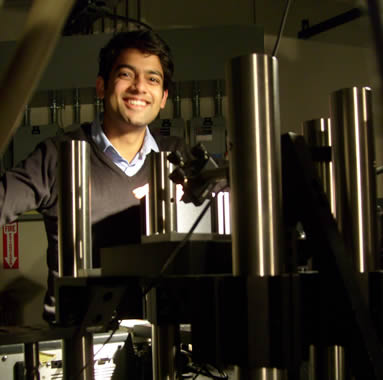 Raoul Correa standing next to a fluorescence microscope in the Bawendi lab.